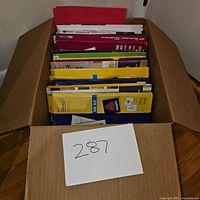 Box filled with various packs of blank greeting and printing cards, visible packaging with multiple colors including yellow, blue, red, and green.