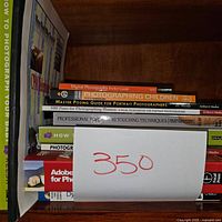 Books on photography and Photoshop stacked on a shelf, showing titles and colorful spines.