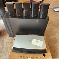 Six small black Bose cube satellite speakers atop black Acoustimass subwoofer and silver/black control console