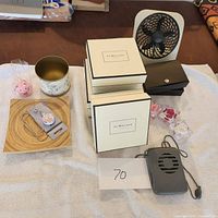 Overview of lot showing Jo Malone white boxes, wooden tray with gold cup and tie clips, small battery charger, and personal fan.