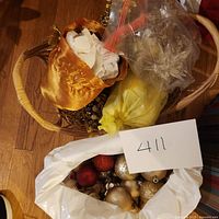 Bags and a small basket holding assorted gold, red, and champagne Christmas ball ornaments.