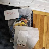 Two bags filled with assorted decorative fabric face masks. One bag is translucent, showing masks with varied patterns including sports and colorful abstract designs.