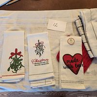 Photo of 5 folded decorative hand towels laid out showing Christmas themed designs and text