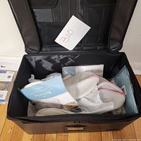 Open black storage bag containing several white mesh laundry wash bags with pink zippers, some packaged.