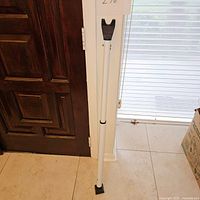 Full view of the white door security kick stand positioned upright between door and floor.