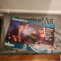 Bolinger exercise mat in original packaging with label showing two people exercising and instructions. Mat is vinyl covered and designed for stretches and exercises.