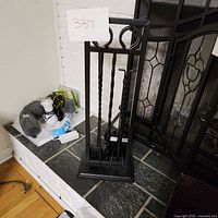 Photo of the full fireplace tool set showing stand and tools from an angle against the fireplace.