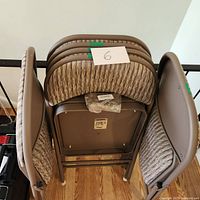 Set of six folding chairs stacked side by side showing the frames and seat undersides.