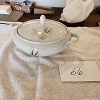 Side view of white porcelain covered bowl with whispering pine design, showing handles on each side.