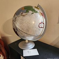 Front angle showing the globe's colorful continents including Asia and parts of Europe, with white stand base.