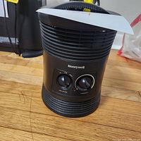 Front view of black Honeywell surround heater with control knobs and brand name visible