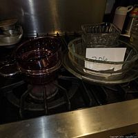 Photo of two purple glass mixing bowls and four clear glass bowls (two square and two round) placed on a stovetop.