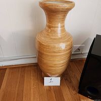 Front view of tall ceramic vase with wood facade showing natural wood grain appearance and shape.