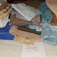 Stack of mixed linen including towels and washcloths of various colors and sizes laid on a bed.