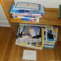 Second shelf containing more folded maps, brochures, and guides with visible titles related to Washington, D.C.