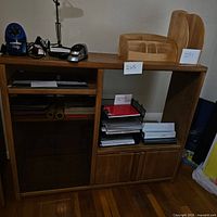 Front view of wood media center with shelves holding office items and lower cupboards