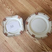 Photo of one square salad plate and one round dinner plate showing decorative floral and gold accents.