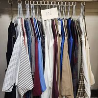 Photo of approximately 20 men's shirts hanging on a rack showing a variety of colors and patterns including stripes, solids, and plaid.