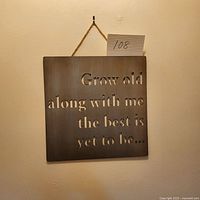 Square metal hanging sign featuring cut-out text 'Grow old along with me the best is yet to be...' suspended by rope.