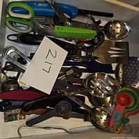 Top view of the entire utensil lot showing various cooking tools including scissors, measuring spoons, ladles, peelers, and slotted spoons clustered together.