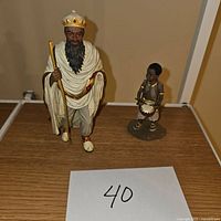 Two nativity figurines including a king figure and a child drummer figure on a wooden surface with label '40' in front.