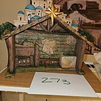 Front view of the ceramic nativity stable showing star and village backdrop.