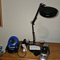 Lot overview showing pencil sharpener, two desk lamps, and electric stapler on wooden desk.