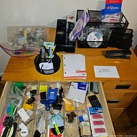 Wide view of the desk with all office supply items arranged, showing file organizers, pen holders, stapler, calculator, and various small items in trays.