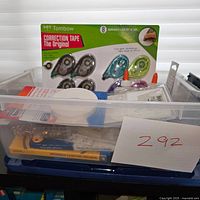 Photo showing various office supplies in a plastic bin including Tombow correction tape and other items