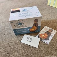 Photo of the unopened OakWay Buddha statue candle holder box with product card and lot number on carpeted floor