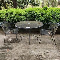 Front view of round table with two chairs on concrete patio