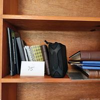 Wooden shelf section with photo albums of different styles including black padded case and fabric-bound albums