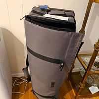 Photo of gray Calumet photography equipment bag stuffed and shot from side angle showing the zipper and handle.