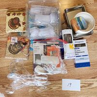 Photo showing plastic clear cutlery in a clear compartmentalized box, paper napkins with turkey design, metal trays, white bowls, and plastic dinnerware sets.