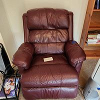 Front view of brown leather recliner chair showing padded seat, back and armrests.