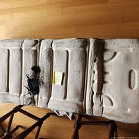 Top view of the beige RelaxZen massage mat showing padded sections for neck and back, with attached wired controller and power adapter placed nearby.