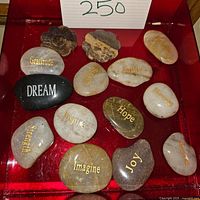 Top view of 13 polished stones with inspirational words and two fossil-like stones.