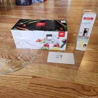 Full set with spiral cutter box, spray oil mister bottle standing next to it, and a clear glass bowl placed in front on wooden flooring.