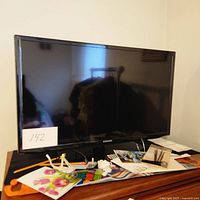 Front view of Samsung 32-inch TV showing screen and frame, placed on table with various items.