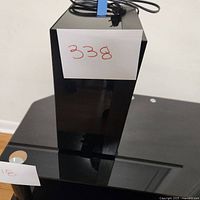 Front view of the black Samsung subwoofer with power cord on top and lot tag attached