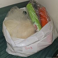 Large white bag filled with white netting fabric and rolls of floral mesh material wrapped in plastic.