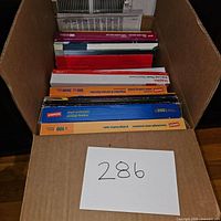 Top view of box with sheet protectors and report cover packs, showing brand Staples and quantities like 200, 100, 3000 sheets