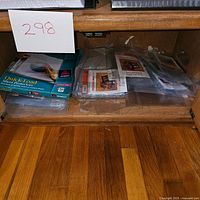 Wide shot of several plastic sheet protector packages inside a wooden cabinet, showing packaging and size variations.