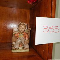 Front view of the ceramic figurine showing a boy playing the flute, dressed in vintage-style clothing.