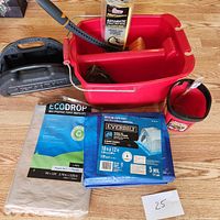 Full lot overview showing red bucket, tarp and drop cloth packages, paint pan, and brushes.