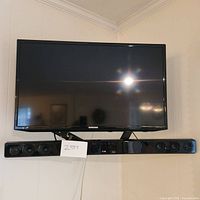 Front view of Samsung 40 inch TV mounted on wall with LG soundbar below it, showing screen and soundbar speakers.