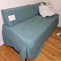 Photo of the twin trundle bed covered with a green quilted fabric showing the back cushions and seat area.