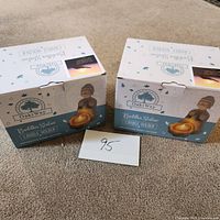 Two boxes of OakiWay Buddha Statue Candle Holders, sealed, placed on carpet.