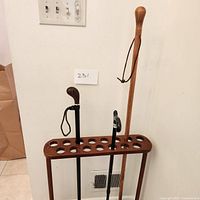 Three walking canes placed in a wooden holder stand, showing overall set and holder