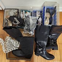 Wide view of the shoe lot showing multiple women's shoes in boxes and containers, including boots, sandals, and heels.